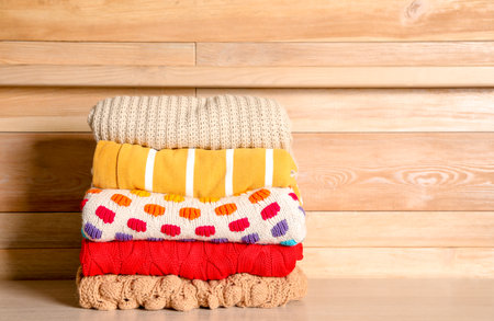 Stack of winter clothes against wooden background. Space for textの写真素材