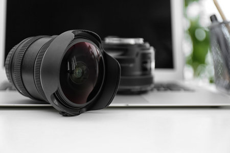 Camera lenses and laptop on white table. Equipment for professional photographerの写真素材