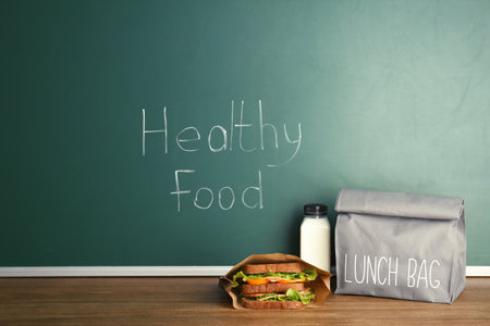 Lunch for school child on table near chalkboard with written Healthy Foodの写真素材