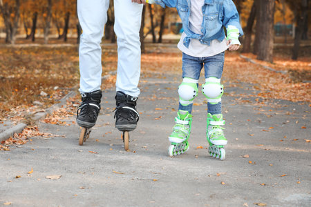 Father and his daughter roller skating in autumn parkの写真素材