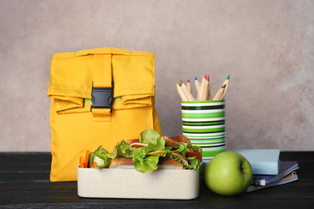 Healthy food for school child and stationery on table near color wallの写真素材