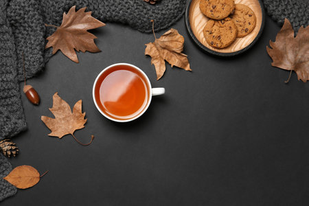 Flat lay composition with hot cozy drink and autumn leaves on dark background. Space for textの写真素材