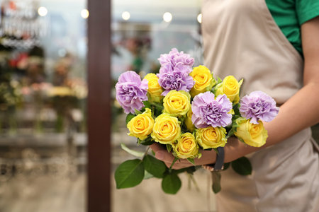 Female florist holding beautiful bouquet in flower shop, closeupの写真素材