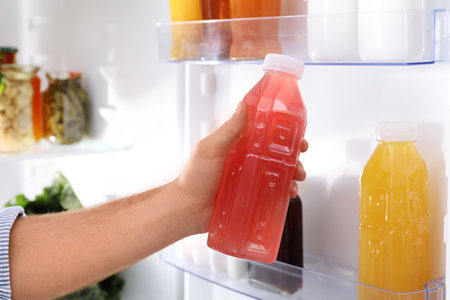 Man taking bottle with juice out of refrigerator in kitchen, closeupの写真素材