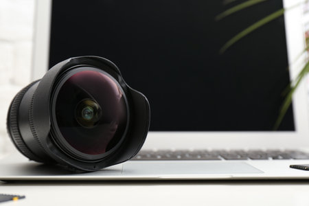 Camera lens on laptop, closeup. Professional photographer's equipmentの写真素材