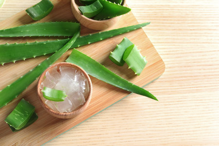 Flat lay composition with bowl of peeled aloe vera and green leaves on wooden tableの写真素材