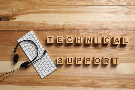 Flat lay composition with words TECHNICAL SUPPORT, headset and computer keyboard on wooden...
