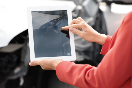 Woman photographing broken car after accident for insurance claim, closeupの写真素材
