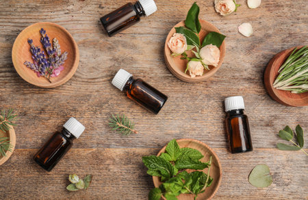 Different essential oils and ingredients on wooden background, flat layの写真素材