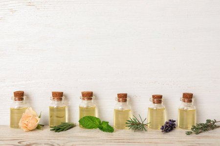Glass bottles with different essential oils and herbs on wooden backgroundの写真素材