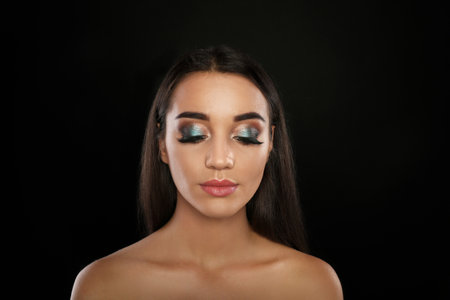 Portrait of young woman with eyelash extensions and beautiful makeup on black backgroundの写真素材