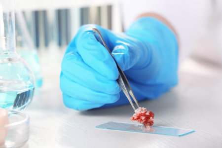 Scientist holding tweezers with forcemeat sample over table, closeupの写真素材