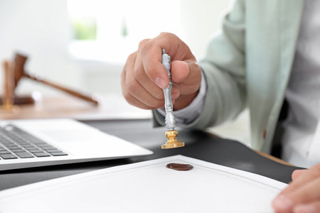 Male notary stamping document at table in office, closeup
