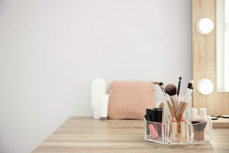 Makeup cosmetic products with tools in organizer on dressing table. Space for textの写真素材