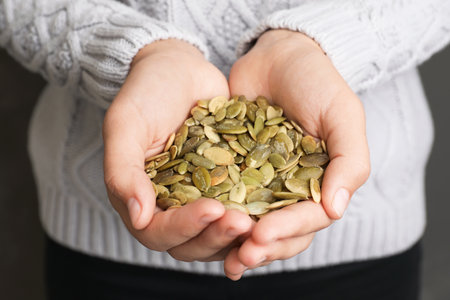 Woman holding raw pumpkin seeds, closeup viewの写真素材
