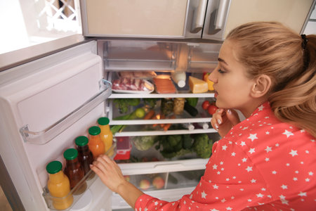 Young woman choosing food in refrigerator at homeの写真素材