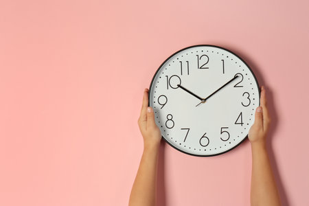 Woman touching clock on color wall, space for text. time management