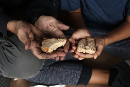 Poor man and his son holding bread, focus on hands