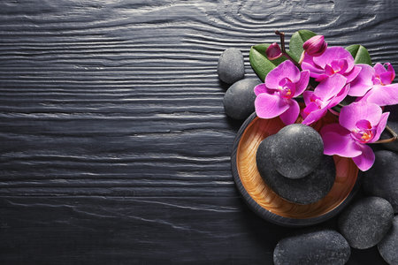 Composition with orchid flowers and spa stones on dark wooden background, top view. Space for textの写真素材