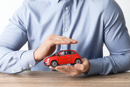Male insurance agent holding toy car, closeupの写真素材