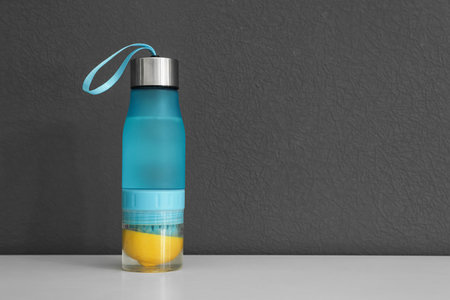 Sport bottle with lemon water on gray background. Space for textの写真素材
