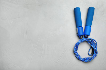 Jump rope and space for text on gray background, top view