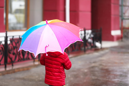 Little girl with umbrella in city on autumn rainy dayの写真素材