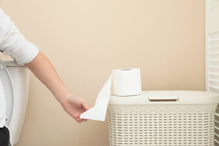 Woman taking toilet paper from roll in bathroom, closeupの写真素材
