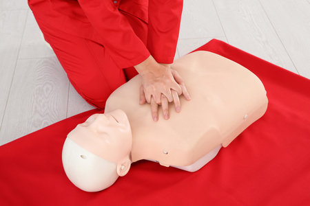 Woman practicing first aid on mannequin indoors, closeup