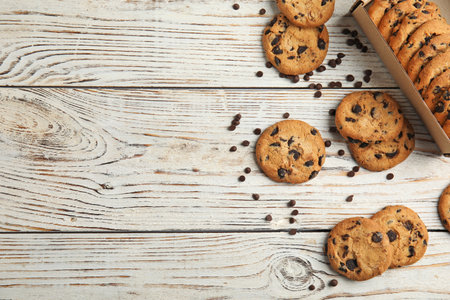 Delicious chocolate chip cookies on wooden table, flat lay. Space for text