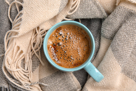 Cup of hot winter drink on warm scarf. Cozy seasonの写真素材