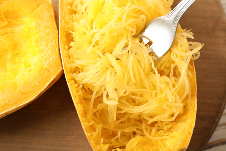 Cooked spaghetti squash and fork on wooden board, top viewの写真素材