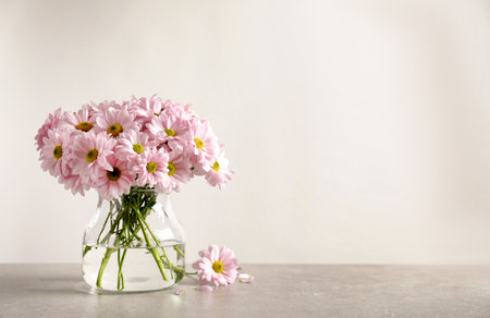 Vase with beautiful chamomile flowers on table against light background. Space for textの写真素材