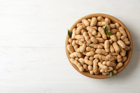 Bowl with peanuts in shell and space for text on wooden table, top viewの写真素材