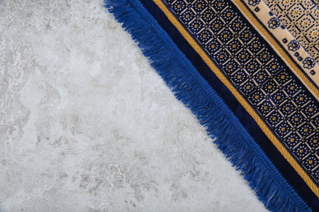 Muslim prayer rug and space for text on gray background, top view