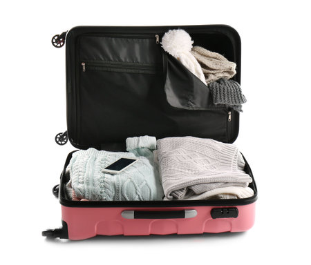 Packed suitcase with warm clothes and smartphone on white background. Space for textの写真素材