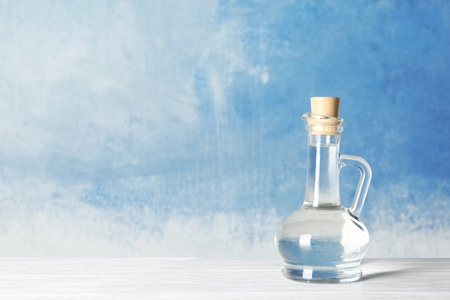 Glass jug with vinegar and space for text on color backgroundの写真素材