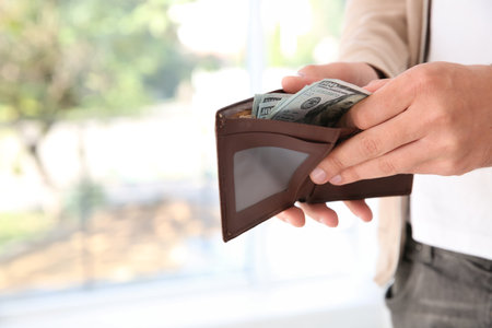 Man holding wallet with money on blurred background, closeup. Space for textの写真素材