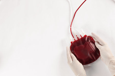 Doctor in gloves holding blood pack on white background, top view. Donation dayの写真素材
