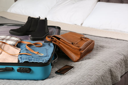 Suitcase packed for trip on bed in room