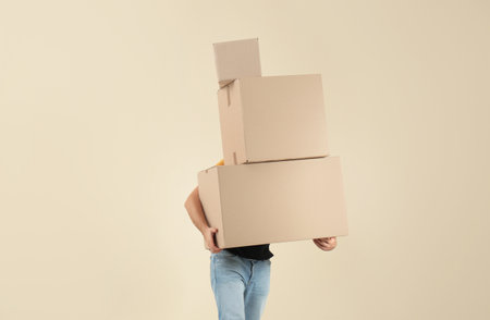Young man carrying cardboard boxes on color background. posture concept