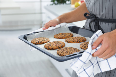 Young man holding oven sheet with cookies in kitchen, closeupの写真素材