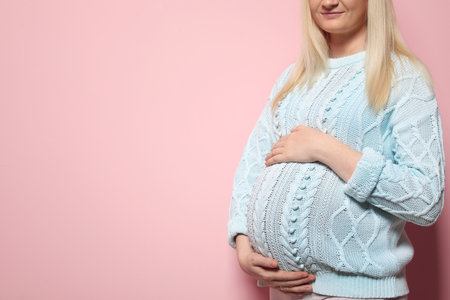 Pregnant woman in sweater on color background. Space for textの写真素材