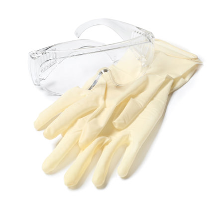 Medical gloves and safety glasses on white background