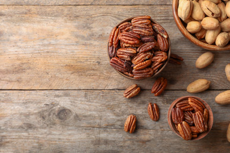 Flat lay composition with tasty pecan nuts on wooden table. Space for text
