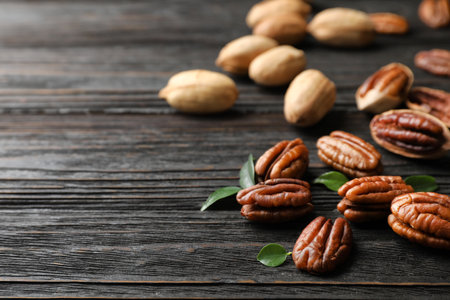 Tasty pecan nuts scattered on wooden table. Space for text