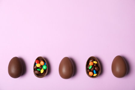Flat lay composition with chocolate Easter eggs and space for text on color backgroundの写真素材