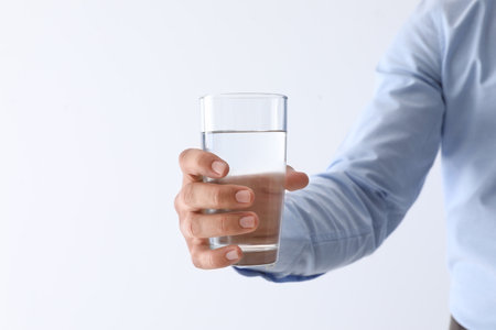 Man holding glass of pure water on white background, closeup. Space for textの写真素材