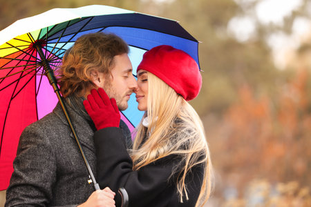 Young romantic couple with umbrella outdoors on autumn dayの写真素材