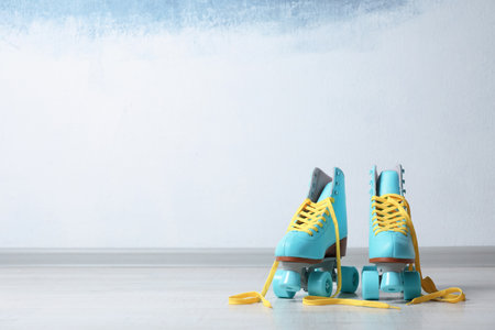 Vintage roller skates on floor near color wall. Space for text